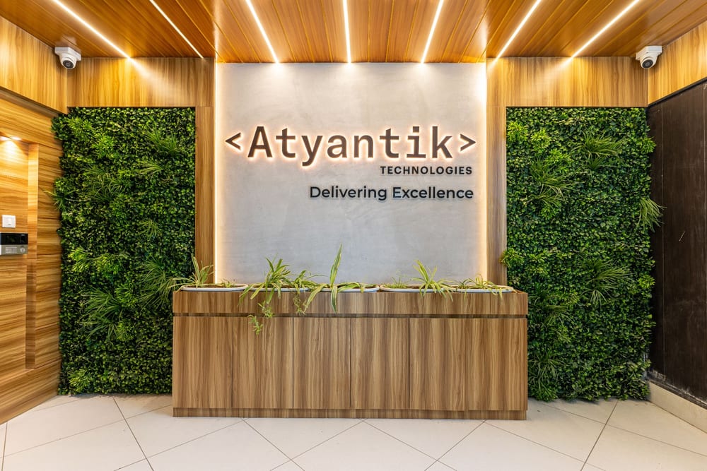 The Atyantik Technologies reception: the Delivering Excellence sign lit above a wood counter set against a living green wall